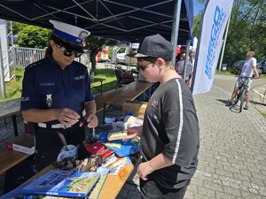 zdjecie policyjnego stoiska policjantka wręcza nagrodę chłopakowi