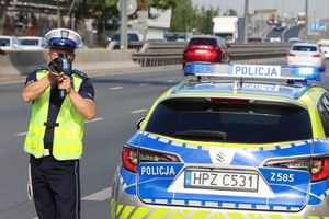 policjant obok radiowozu mierzy prędkość