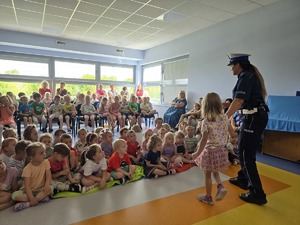 policjantka stoi z dziewczynką na środku sali uczniowie siedzą