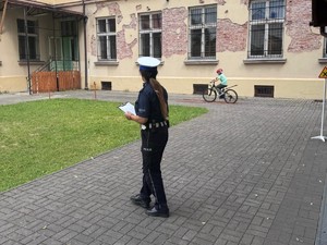 policjantka tyłem w tle uczeń jedzie na rowerze po torze