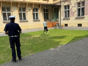 policjant stoi tyłem w tle uczeń jedzie na rowerze