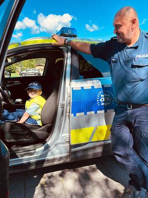 na zdjęciu policjant i dziecko e radiowozie