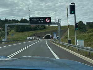 zdjęcie kolorowe z auta, droga ekspresowa a nad nią napis &quot;tunel otwarty&quot;