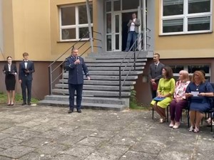 zdjęcie kolorowe, policjant przemawia na tle bydynku