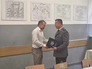 policjant przekazuje list gratulacyjny dyrektorowi placówki