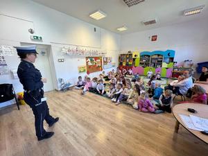 zdjęcie kolorowe w przedszkolu, policjantka stoi przed dziećmi