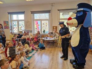 zdjęcie kolorowe w przedszkolu, policjantka i sznupek stoją przed dziećmi