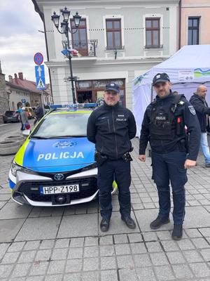 Dwóch policjantów przy radiowozie biorący udział w obchodach