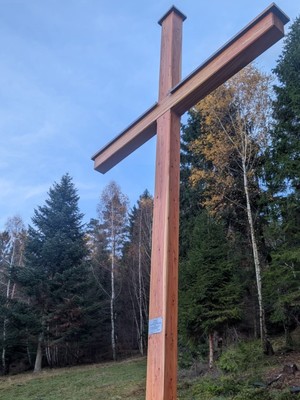 Zdjęcie przedstawiające krzyż przy masywie leśnym