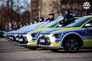 Oznakowane radiowozy policyjne ze stojącymi obok policjantami