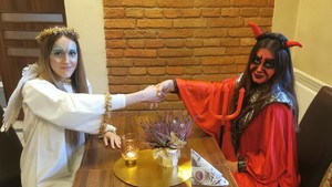 Osoby przebrane za anioła i diabła ściskają sobie dłonie