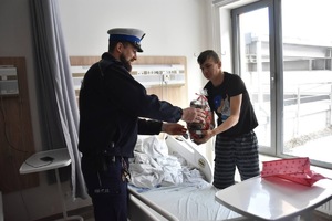 zdjęcie kolorowe w szpitalu, policjant rozdaje chłopcu prezenty