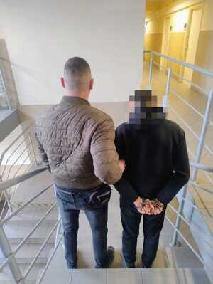 Zdjęcie przedstawia zatrzymanego nietrzeźwego kierującego, którego prowadzi policjant