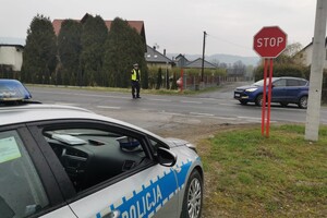 Zdjęcie przedstawia policjanta ruchu drogowego dokonującego pomiaru prędkości miernikiem