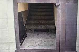 Zdjęcie przedstawia uszkodzone drzwi wejściowe na klatkę schodową