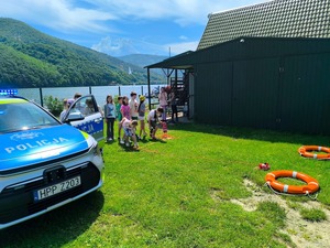Zdjęcie przedstawia dzieci ze szkoły podstawowej podczas prelekcji prowadzonej przez policjanta w związku z akcja profilaktyczną "Kręci mnie bezpieczeństwo w lecie"